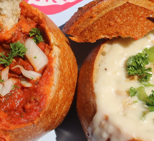 Close up of red and white clam chowder in sourdough bread bowls