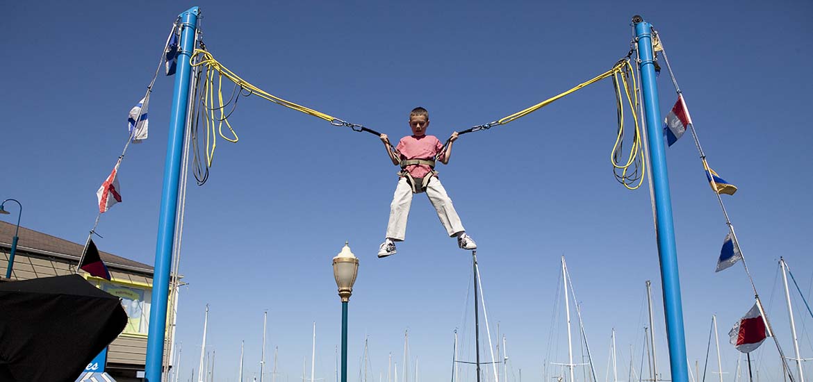 Boy in red shirt and white pants in air on bungee ride