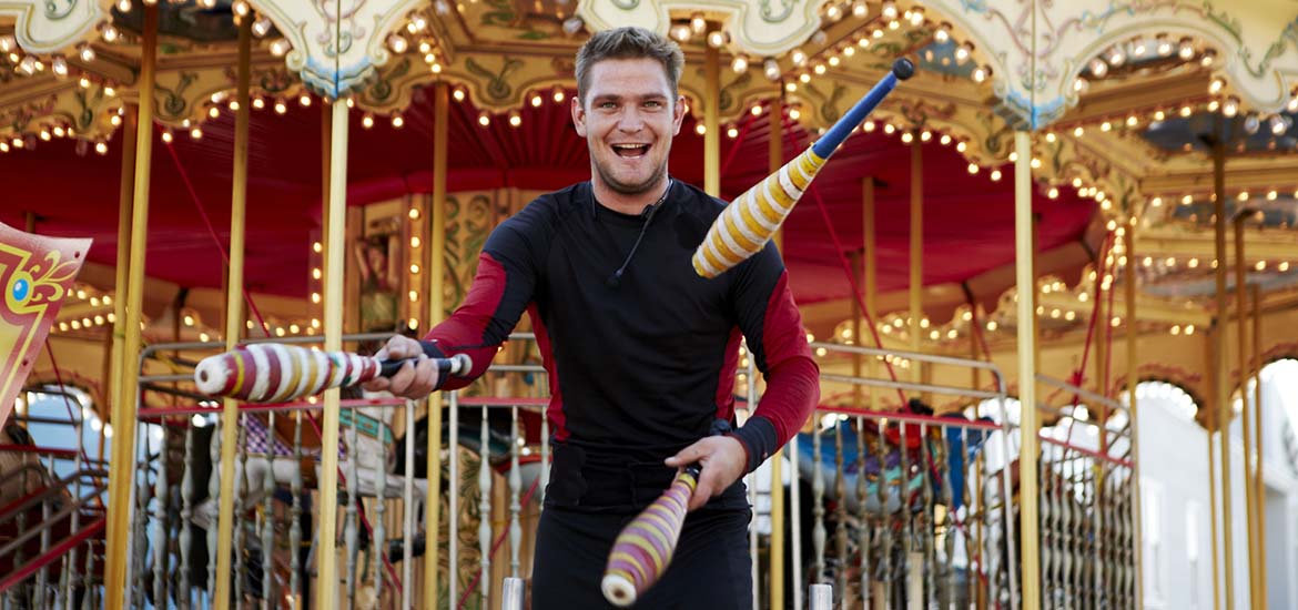 Street performer juggling at PIER 39 in front of the carousel